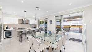 Een moderne keuken met witte kasten, een glazen eettafel en uitzicht op de omgeving.