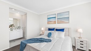 A bedroom with a bed, nightstands, a mirror, and artwork on the wall. - 3 Ebbtide Way, Corlette (Corlette)