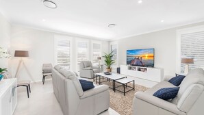 Een moderne woonkamer met een flatscreen televisie, twee banken, een salontafel en een potplant.