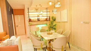 A dining area with a marble table, cushioned chairs, pendant lighting, and a plant. - Eleven Apartments (Galadimawa)