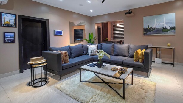 A modern living room with a sectional sofa, a coffee table, a small side table, and a TV. - Eleven Apartments (Galadimawa)