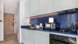 A modern kitchen with a blue countertop, a coffee machine, a stove, and an oven. - Luxury Burj Khalifa & Canal View Studio (Dubai)