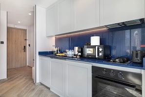 Eine moderne Küche mit blauer Arbeitsplatte, einer Kaffeemaschine, einem Herd und einem Backofen.