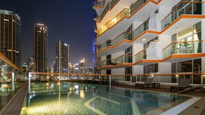 A rooftop pool with a view of a cityscape at night.