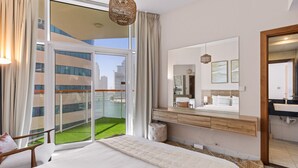 Ein Hotelzimmer mit Bett, Badezimmer mit Spiegel, Balkon mit Blick auf Gebäude und Wasser sowie einer Pendelleuchte.