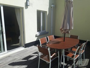 A round wooden table with six chairs, an umbrella, and a sliding glass door leading to a balcony. - 2 Bed Apartment-Large Sunny Terrace Early check-in (Dublin)