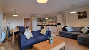 A compact living space with a sofa, a coffee table, a dining area, and a kitchenette. - Spacious 2 Bed Apartment w/balcony (Dublin 8)