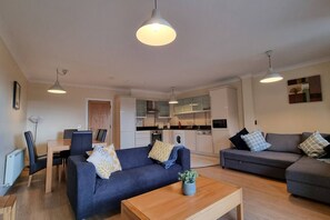 A compact living space with a sofa, a coffee table, a dining area, and a kitchenette. - Spacious 2 Bed Apartment w/balcony (Dublin 8)
