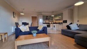 A modern living room with a sofa, a coffee table, and a dining area. - Spacious 2 Bed Apartment w/balcony (Dublin 8)