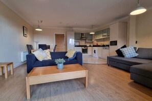 A modern living room with a sofa, a coffee table, and a dining area.