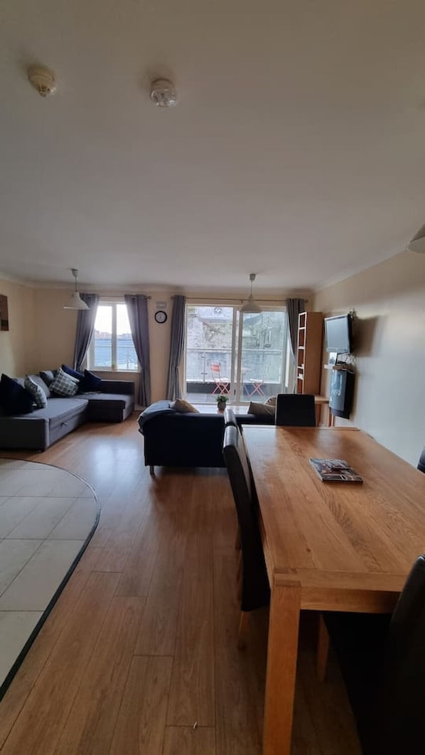 Una sala de estar con un sofá, una mesa de comedor y un televisor.