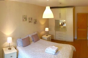 Un dormitorio con cama, lámparas de noche, armario y espejo.