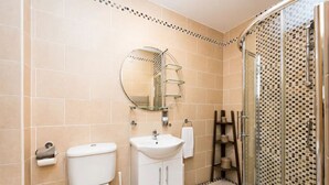 A bathroom with a toilet, sink, mirror, shower, and tiled walls. - Spacious 2 Bed Apartment w/balcony (Dublin 8)