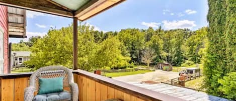 A wooden deck with wicker furniture, a clear view of a green landscape, and a distant building.