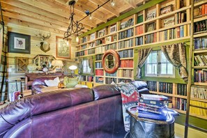 A cozy room with a leather sofa, a bookshelf filled with books, a globe, and a bicycle hanging from the ceiling.