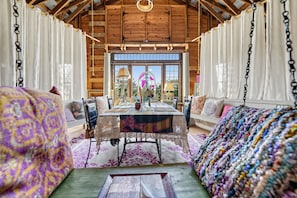 A cozy room with a wooden ceiling, a dining table, and a view of the outdoors.