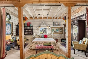 Un dormitorio acogedor con cama, mesitas de noche, cómoda y una ventana con una obra de arte.