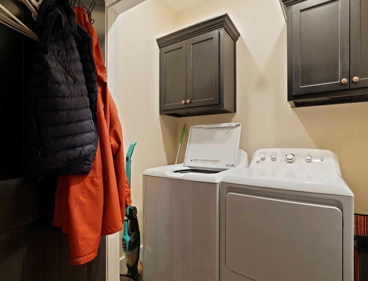 A laundry alcove with a white washer, dryer, and dark cabinetry.