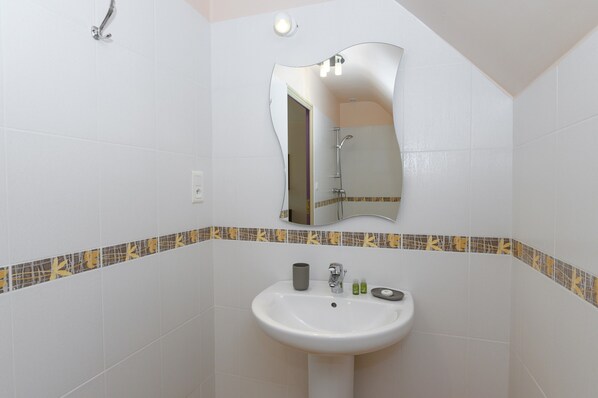 A bathroom with a white sink, a mirror, and a shower.