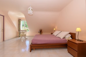 A bedroom with a bed, bedside table, lamp, window, and a chair.