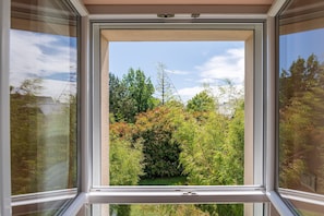 Una ventana con vistas a un jardín y árboles.