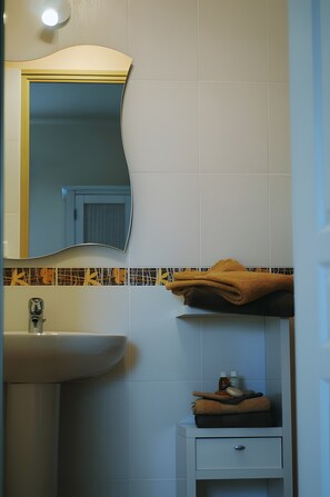 Un bagno con lavandino, specchio, portasciugamani e un piccolo armadietto.