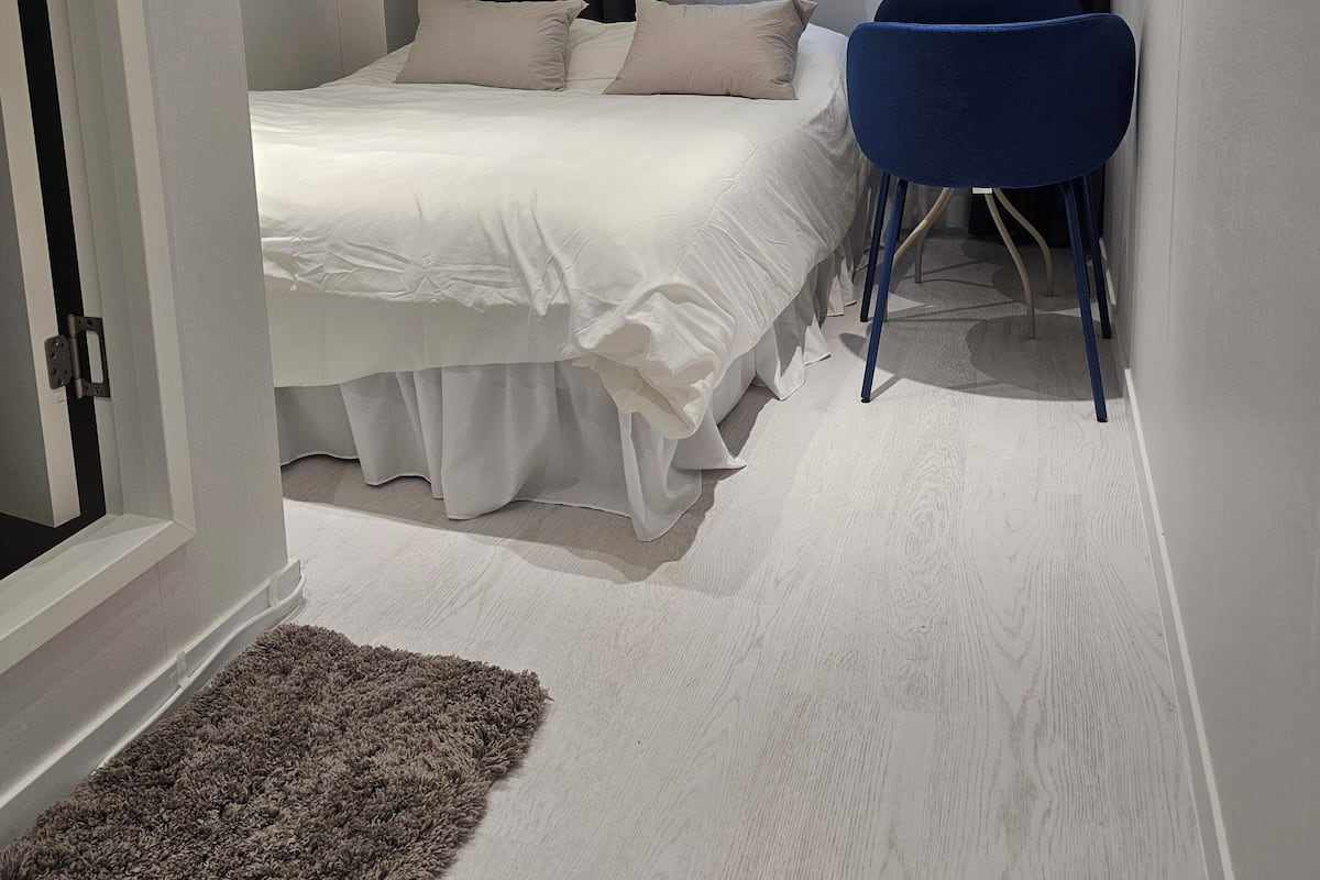 Une chambre à coucher avec un lit, une chaise, une fenêtre avec des rideaux et une porte.