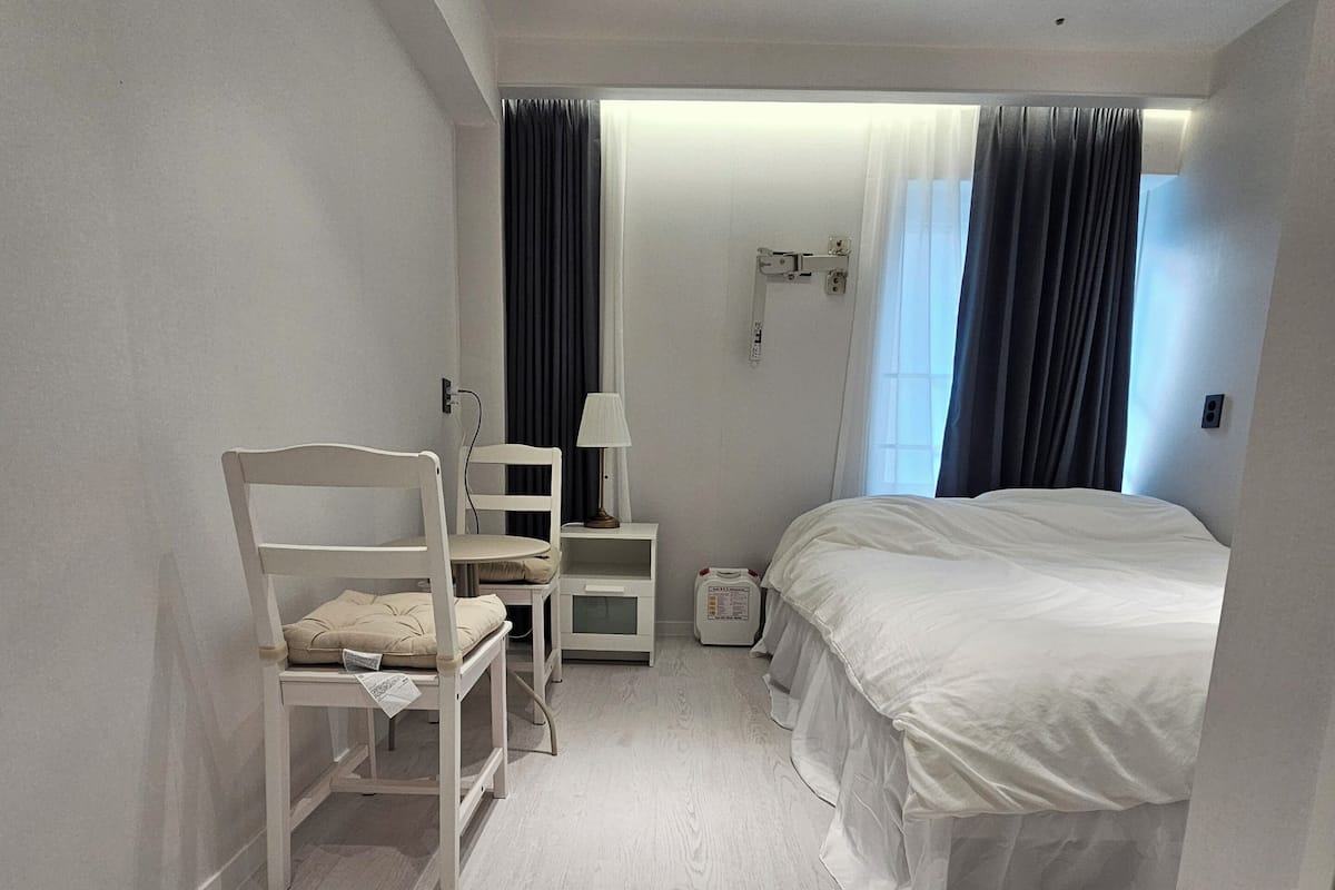 Une chambre à coucher avec un lit, une chaise, une table de chevet et une lampe.