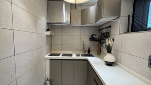 A modern kitchen with a central island, a built-in oven, and a pendant light. - The dongdaemun hostel (Seoul)