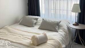 A neatly made bed with pillows, a bedside lamp, and sheer curtains. - The dongdaemun hostel (Seoul)