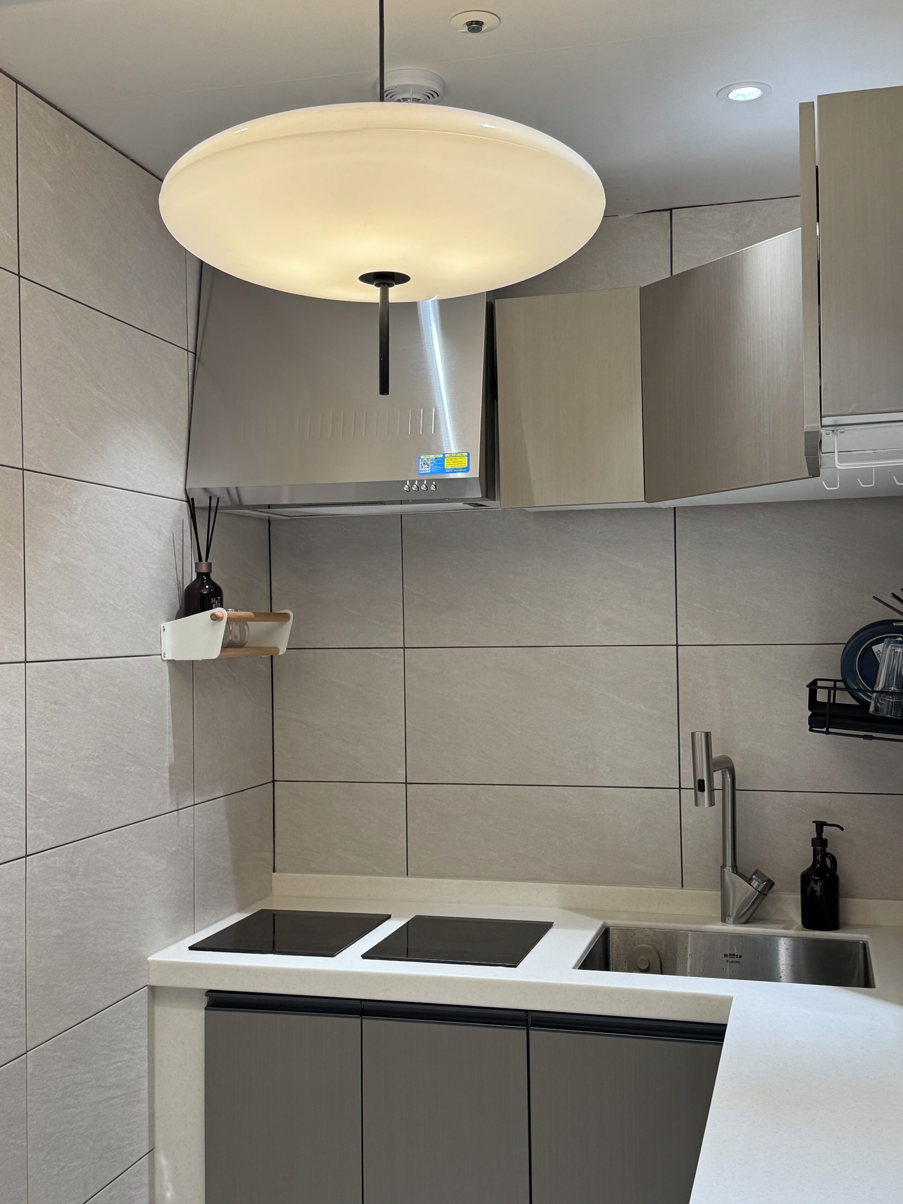 Una cocina moderna con estufa integrada, un lavamanos y una lámpara colgante.