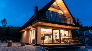 A modern house with a large glass window, a wooden deck, and a balcony. - Holiday Home With Sauna and Mountain View (Bukowina Tatrzanska)