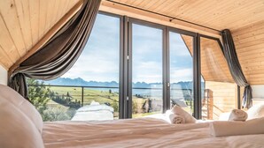 A bedroom with a large window, wooden ceiling, and a bed with white linens. - Holiday Home With Sauna and Mountain View (Bukowina Tatrzanska)