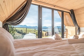 A bedroom with a large window, wooden ceiling, and a bed with white linens. - Holiday Home With Sauna and Mountain View (Bukowina Tatrzanska)