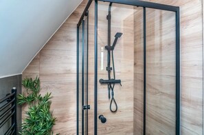A modern shower enclosure with a wooden panel wall, metal frame, and a plant beside it. - Holiday Home With Sauna and Mountain View (Bukowina Tatrzanska)