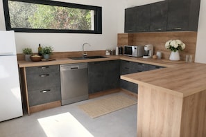A modern kitchen with a dishwasher, sink, microwave, and coffee maker. - Villa Chêne et mer Boulouris Plage (Saint-Raphaël)