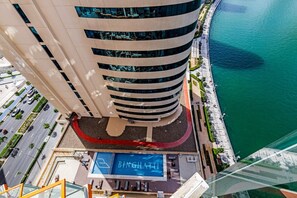 Een hoog hotel met een zwembad, een gebogen gevel en uitzicht op het water.