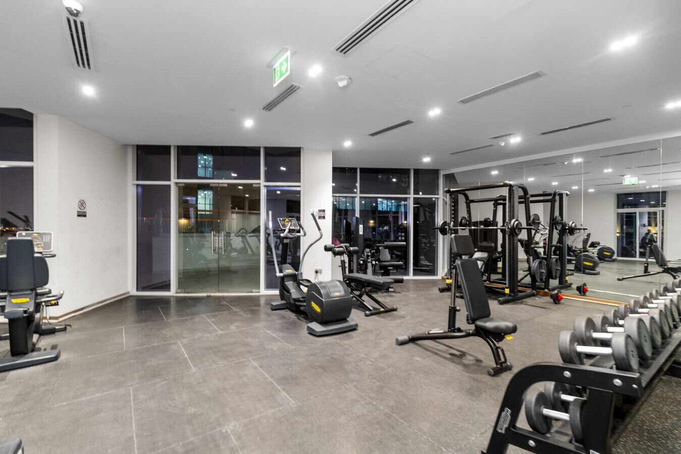 Un gimnasio moderno con diversos equipos de ejercicio, ventanas amplias y un diseño limpio y espacioso.