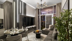 A modern living room with a large TV, dining area, and a sofa. - Gogoto4 2BR Premium Canal & Burj Khalifa View (Dubai)