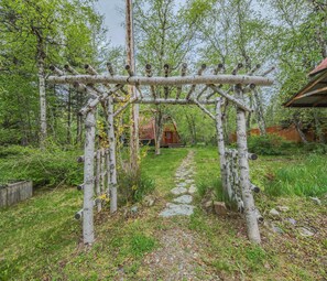 Ein rustikaler Holzbogen mit einem Steinpfad, der zu einer Hütte führt.