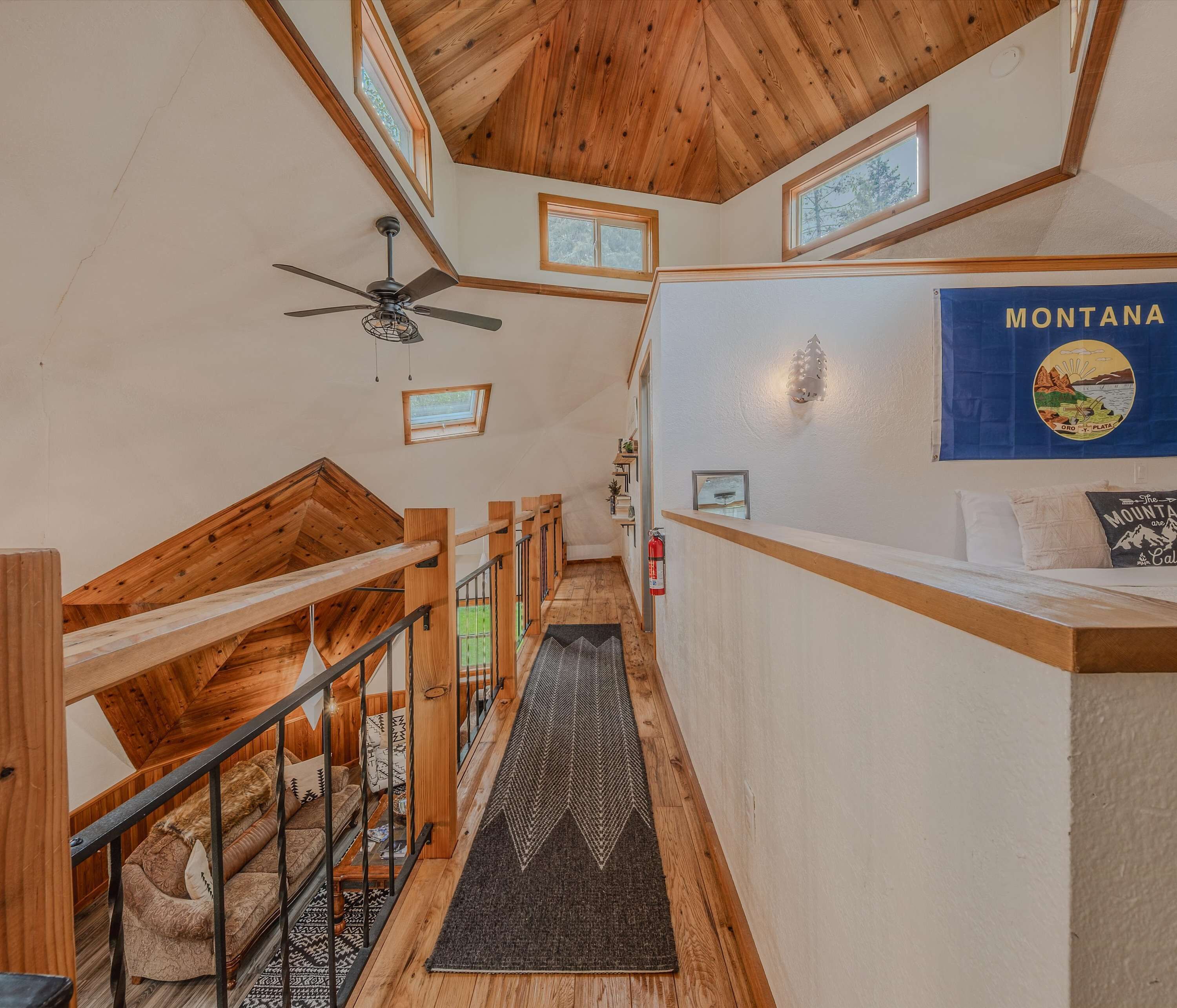 A wooden interior with a staircase, a ceiling fan, a wall-mounted light, and a sign reading 'MONTANA'.
