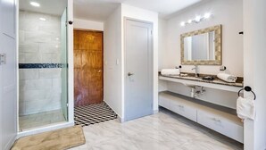 A modern bathroom with a shower, vanity, and a large mirror. - Hotel Room With Ocean-view Rooftop Infinity Pool, AC, Gym - Dog-friendly (Cabo San Lucas)