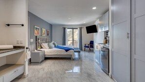 A modern bedroom with a bed, bedside table, and a TV mounted on the wall. - Hotel Room With Ocean-view Rooftop Infinity Pool, AC, Gym - Dog-friendly (Cabo San Lucas)