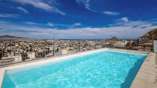 A rooftop pool with a cityscape view, surrounded by a metal fence. - Hotel Room With Ocean-view Rooftop Infinity Pool, AC, Gym - Dog-friendly (Cabo San Lucas)