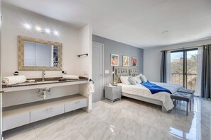 A modern bedroom with a large bed, a vanity with a mirror, and a nightstand. - Hotel Room With Ocean-view Rooftop Infinity Pool, AC, Gym - Dog-friendly (Cabo San Lucas)