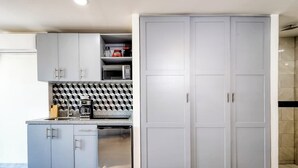 A modern kitchen with grey cabinets, a microwave, and a coffee maker. - Hotel Room With Ocean-view Rooftop Infinity Pool, AC, Gym - Dog-friendly (Cabo San Lucas)