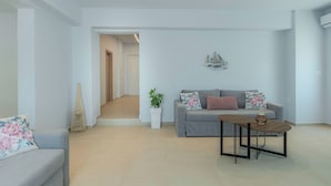 A modern living room with a grey sofa, a small wooden table, and a potted plant.