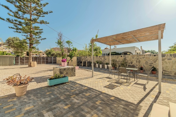 An outdoor patio area with a pergola, seating, and potted plants. - Aspasia House (Platanias)