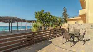 An outdoor patio with a table and chairs, a pergola, and a view of the sea.
