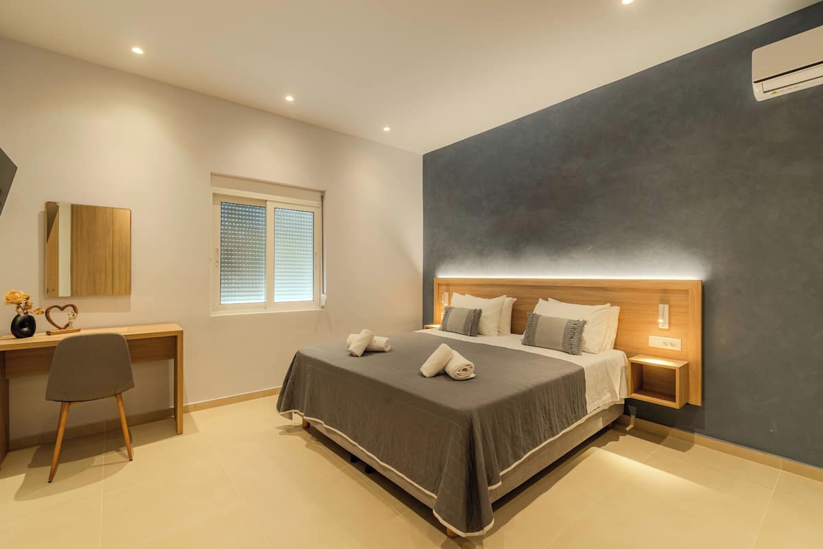 A modern bedroom with a large bed, bedside tables, a desk, and a chair.